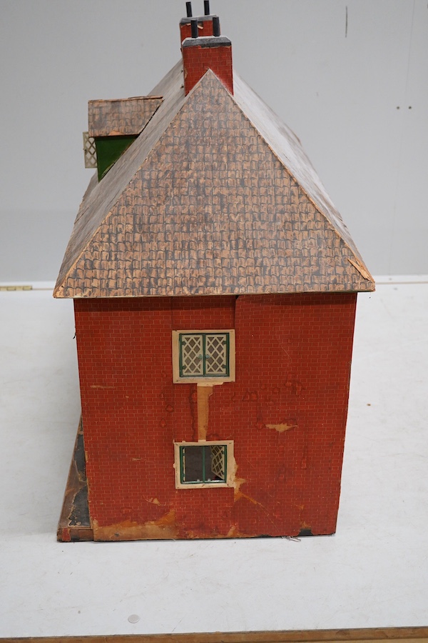 A 1920s/30s commercially produced dolls house, possibly by Tri-ang, of plywood construction, overlaid with printed paper roof tiles and brickwork, and tinplate windows and window frames, comprising of four rooms with bay